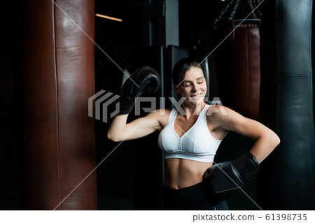 Boxing woman posing with punching bag, on dark background. Strong and independent woman concept 61398735