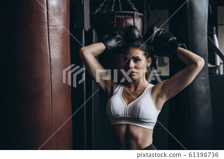 Boxing woman posing with punching bag, on dark background. Strong and independent woman concept 61398736