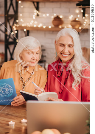 Two grey-haired pleasant cute ladies looking interested while studying together 61399689