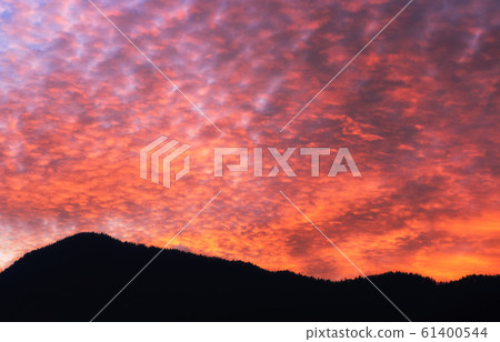 Colorful evening orange Altocumulus clouds on the sky and silhouette of mountains at background Colorful evening orange Altocumulus clouds on the sky and silhouette of mountains at background 61400544