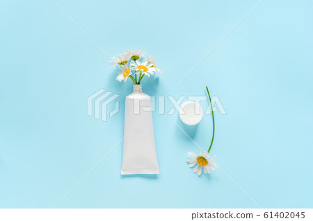 Bouquet of chamomile flowers from cosmetic, medical white tube for cream, ointment, toothpaste or other product. Concept natural herbal organic cosmetics, homeopathic cosmetology Mockup Copy space 61402045