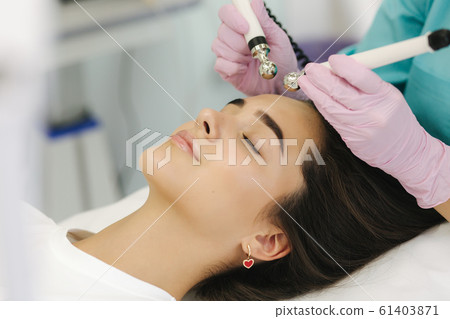 Close up of female face with soft skin. Woman at cosmetology clinic taking a beauty procedure for skin clining. Electrophoresis Close up of female face with soft skin. Woman at cosmetology clinic taking a beauty procedure for skin clining. Electrophoresis 61403871