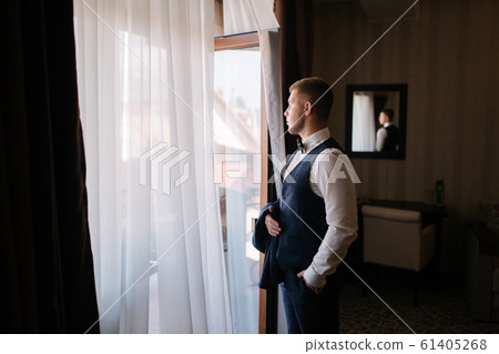 Handsome young groom dressed at hotel. Morning in hotel Handsome young groom dressed at hotel. Morning in hotel 61405268