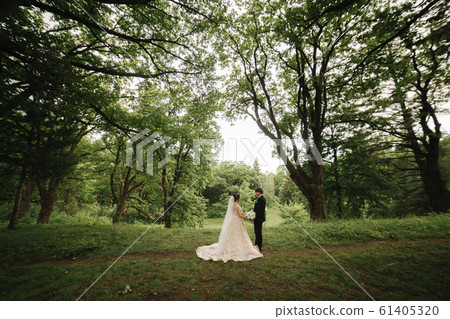 Just married coupleon green background, broom and bride walking in the forest 61405320