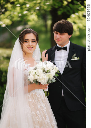 Happy groom and bride walking in the park. Charming woman with handsome man spend time together Happy groom and bride walking in the park. Charming woman with handsome man spend time together 61405666