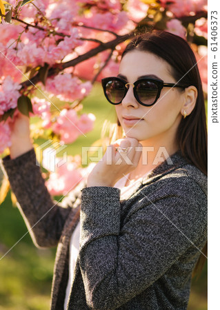 Portrait of beautiful woman in sunglasses stand by the pink tree Portrait of beautiful woman in sunglasses stand by the pink tree 61406373