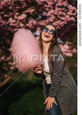Beautiful brown hair model hold a cotton candy in hands and give a kiss. Young woman with pink cotton candy 61406501