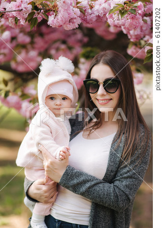 Portrait of mother and her little baby girl. Beautiful mom and cute baby. Mother hug her daughter. Baby dressed in peanch colour hat and smile 61407202