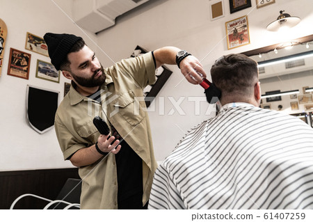 Men's haircut. Stylish hairdresser cuts a man. 61407259