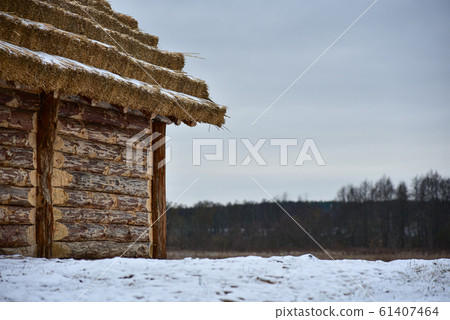 Wooden log cabin with a thatched roof in winter Wooden log cabin with a thatched roof in winter 61407464