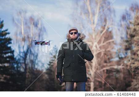 Hipster man with flying drone in the park Hipster man with flying drone in the park 61408448