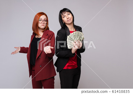 Rich business woman smiling holding heap of cash Rich business woman smiling holding heap of cash 61410835