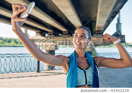 Beautiful sporty woman making selfie flexing her muscles 61411214