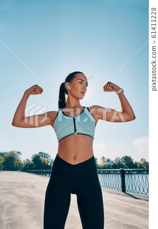 Strong and confident beautiful woman flexing her muscles Strong and confident beautiful woman flexing her muscles 61411228