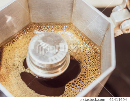 Italian traditional coffeemaker with hot coffee flowing out from the spout 61411694