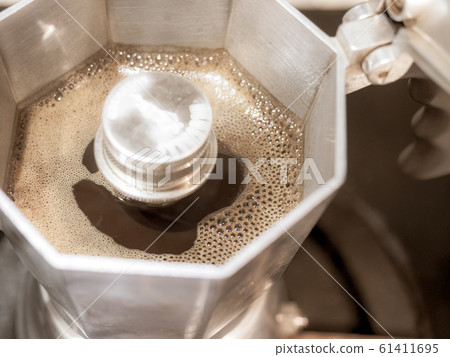 Italian traditional coffeemaker with hot coffee flowing out from the spout Italian traditional coffeemaker with hot coffee flowing out from the spout 61411695