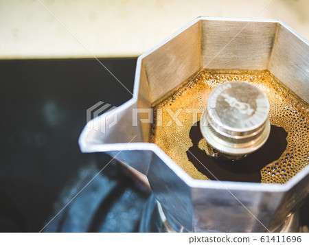 Italian traditional coffeemaker with hot coffee flowing out from the spout Italian traditional coffeemaker with hot coffee flowing out from the spout 61411696