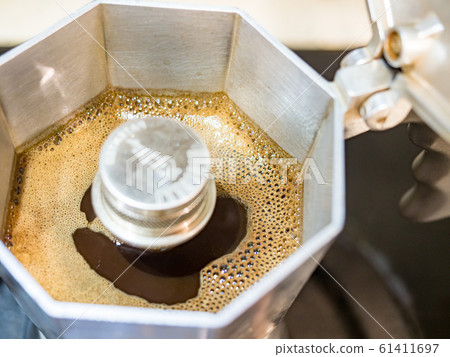 Italian traditional coffeemaker with hot coffee flowing out from the spout Italian traditional coffeemaker with hot coffee flowing out from the spout 61411697