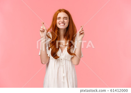 Pretty please may my dream come true. Wishful and nervous cute redhead girl have secret desire, cross fingers good luck, making wish with all effort, close eyes and clench teeth as praying 61412000