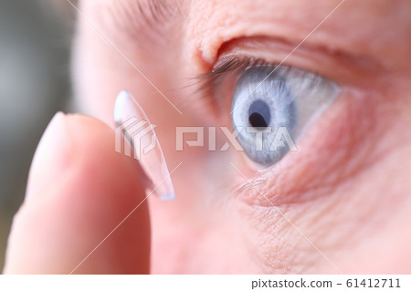 Man putting on soft contact lens Man putting on soft contact lens 61412711