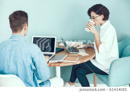 Young woman is drinking hot drink in office 61414085