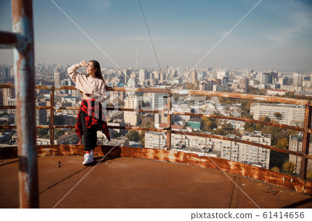 Attractive girl is holding hand near eyes on rooftop Attractive girl is holding hand near eyes on rooftop 61414656