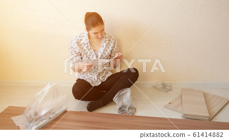 housewife sits and reads instruction looking at fasteners 61414882