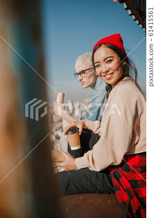 Happy Asian lady holding coffee on the roof Happy Asian lady holding coffee on the roof 61415561