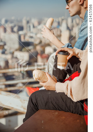 Young woman sitting with hot dring on the rooftop Young woman sitting with hot dring on the rooftop 61415566