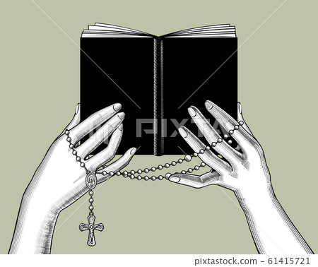 Hands holding a black book and prayer beads 61415721