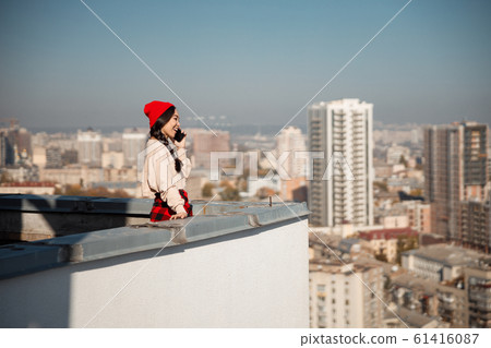 Happy pretty lady talking on mobile phone on roof Happy pretty lady talking on mobile phone on roof 61416087