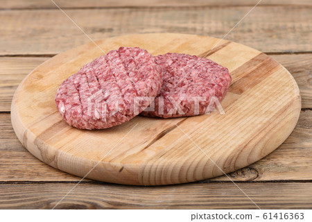 Two raw pink beef cutlets on a cutting board.. Two raw pink beef cutlets on a cutting board.. 61416363