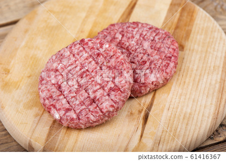Soft focus. Two raw pink beef cutlets on a cutting board. Soft focus. Two raw pink beef cutlets on a cutting board. 61416367