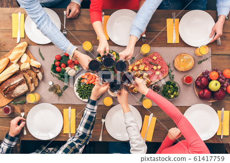 Family sitting behind table and clinking beverage glasses Family sitting behind table and clinking beverage glasses 61417759