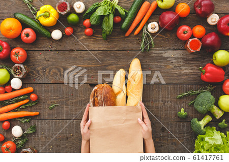 Woman hands with bread near raw organic vegetables on table Woman hands with bread near raw organic vegetables on table 61417761