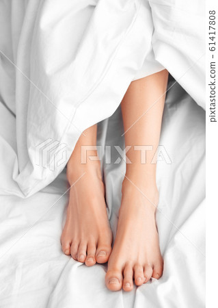 Morning at Home. Woman lying on bed legs under blanket top view close-up 61417808