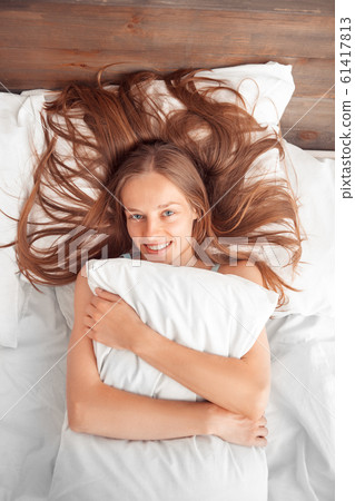 Morning at Home. Woman lying on bed hugging pillow laughing cheerful top view Morning at Home. Woman lying on bed hugging pillow laughing cheerful top view 61417813