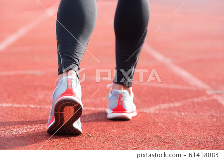 Athletic person on running track getting ready to start run, back view. 61418083