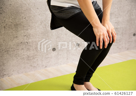 Woman doing knee rotation Woman doing knee rotation 61426127