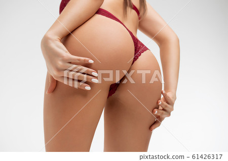 Crop alluring female with hands on buttocks 61426317