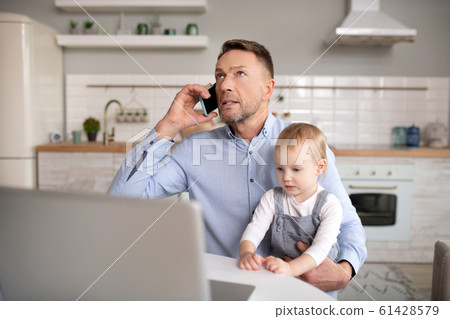 Mature father having a phone call and holding his daughter 61428579