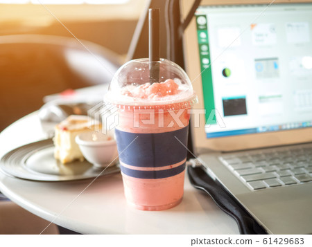 Businesswomen drinking strawberry smoothie fresh and cake sweet dessert health food lifestyle between work freelance.Laptop Notebook computer technology digital is on table wood sofa black color 61429683