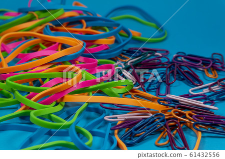 Colorful rubber bands and paper clips over blue 61432556