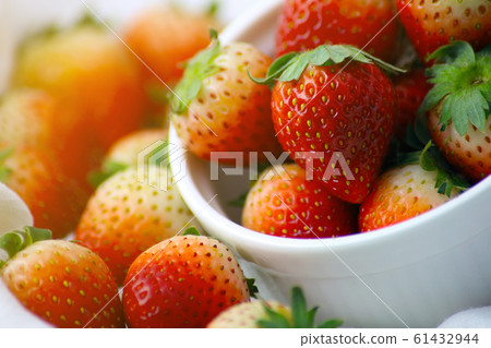 Fresh strawberries in a white cup, Put on the white fabric backing pad, On the white table. 61432944