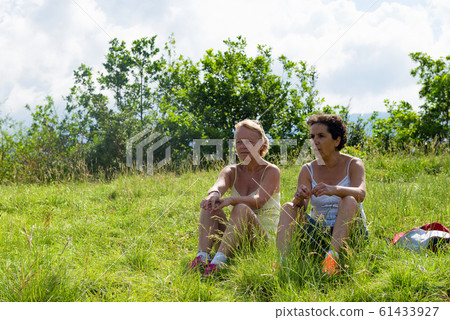 Two women resting, and sitting in the grass 61433927