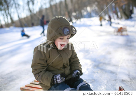 Boy sledding on the street in the snowy winter in the mountains 61438503