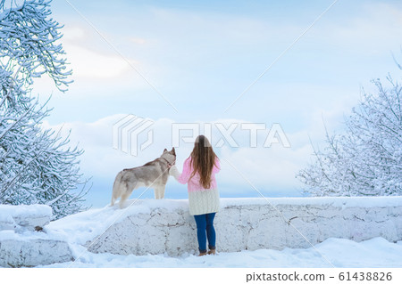 A young woman together with a dog conquer the snowy peaks A young woman together with a dog conquer the snowy peaks 61438826