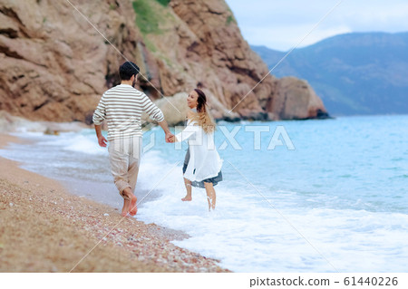 Frame shoot of couple walking on beach together in love holding each other by hand. Frame shoot of couple walking on beach together in love holding each other by hand. 61440226