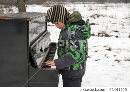 Boy playing piano outdoors 61441339
