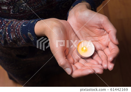 Praying with candle. Candle in hands. Females hands with can Woman against abortion. Tea candle in 61442169